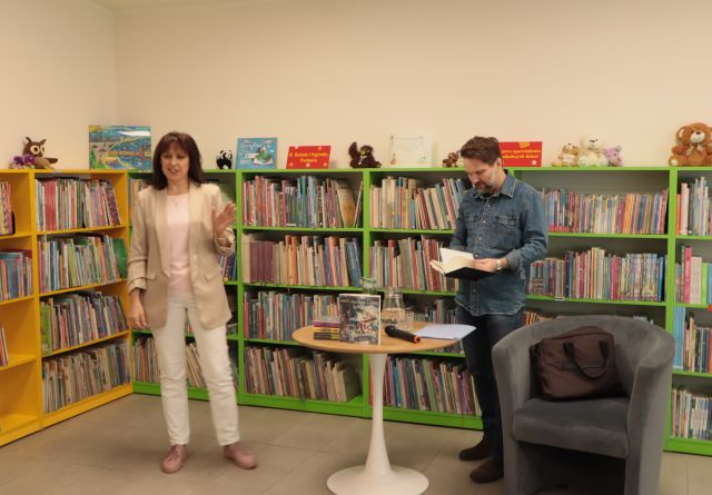 na zdjęciu dyrektorka biblioteki i pisarz, w tle regały z książkami