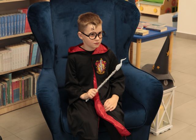 chłopiec siedzi na niebieskim fotelu i pozuje do zdjęcia w stroju Harry'ego Pottera