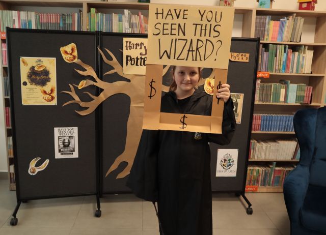 dziewczynka pozuje do zdjęcia z ramką i w stroju Harry'ego Pottera