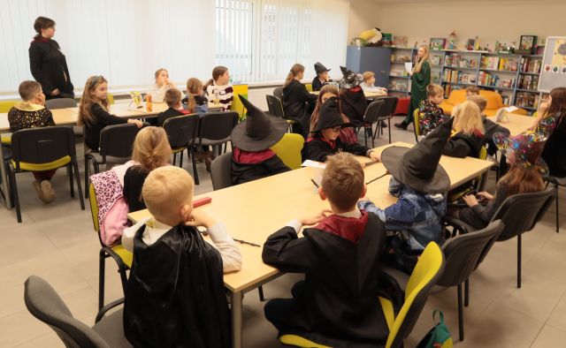 przy stołach siedzą dzieci w strojach z Harry'ego Pottera