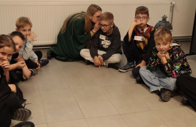 dzieci siedzą na podłodze i bawią się w głuchy telefon