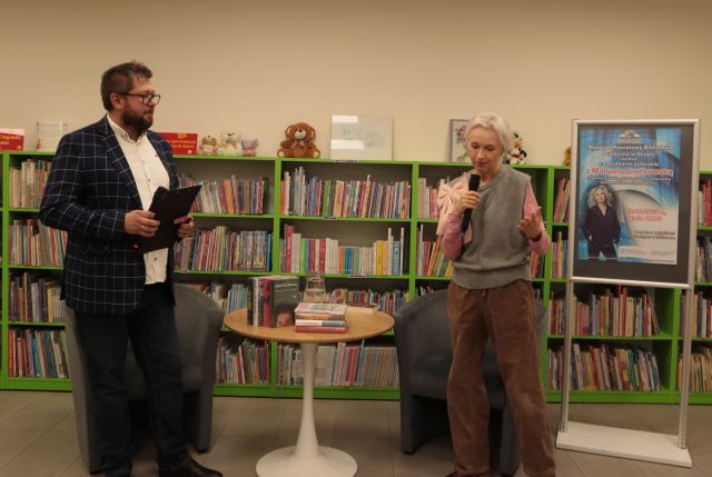 prowadzący i autorka stoją z mokrofonami, w tle regały z książkami