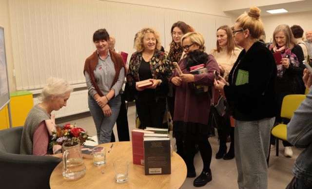 autorka podpisuje książkę, przed nią stoją kobiety