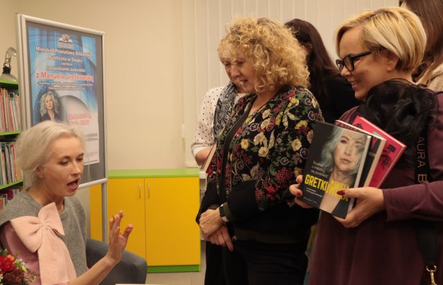 kobiety stoją przed siedzącą autorką