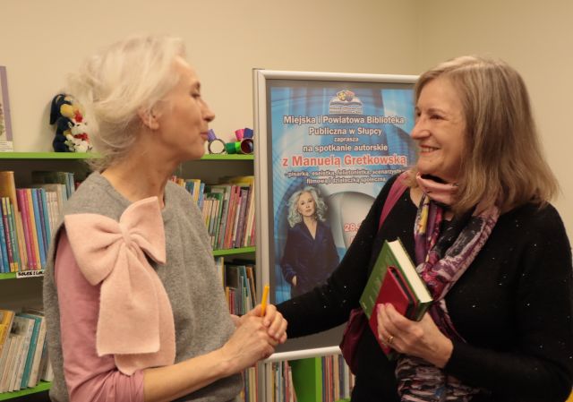 kobieta z książką ściska dłoń z Manuelą Gretkowską