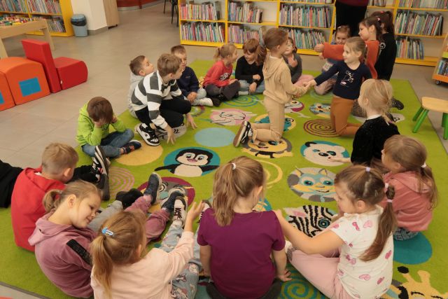 przedszkolaki siedzą na kolorowym dywanie