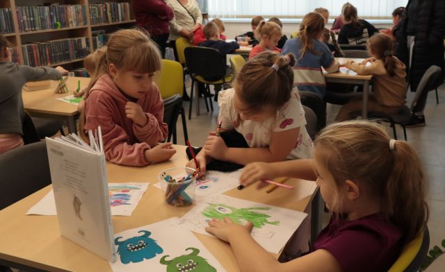 przedszkolaki przy stolikach malują potworki