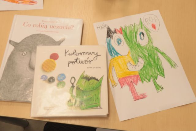 rysunek dziecka przedstawiający kolorowego potworka i dwie książki