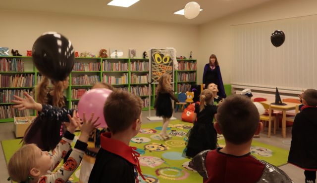 dzieci bawią się balonami, w tle regały z książkami