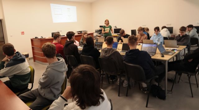 młodzież w sali komputerowej, przed nimi stoi prowadząca szkolenie
