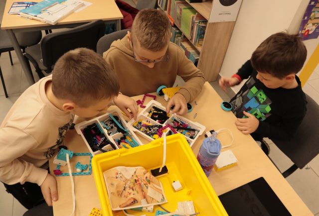 3 chłopców buduje robota z klockó Lego