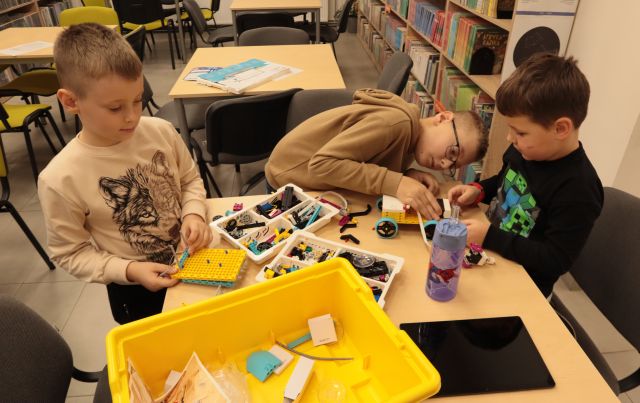 chłopcu budują robota z klocków Lego