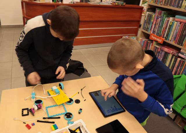 2 chłopców buduje robota z klocków Lego, używając tableta