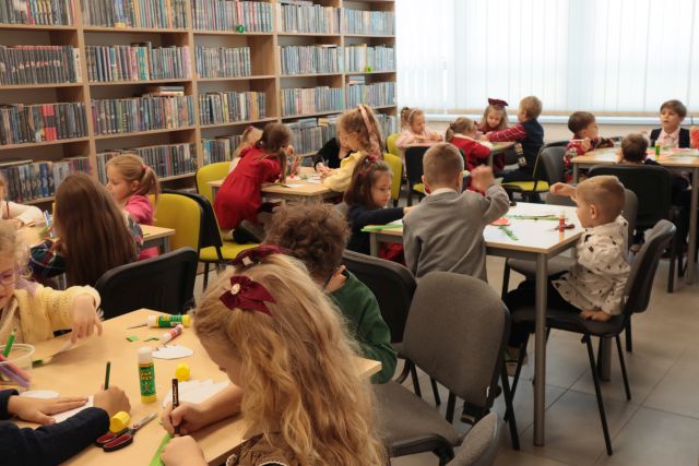 przedszkolaki siedzą przy stołach, rysują, wycinaja i kleją tulipany z kartki