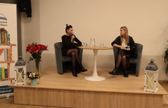 na scenie siedzi autorka mówiąca do mikrofonu i prowadząca