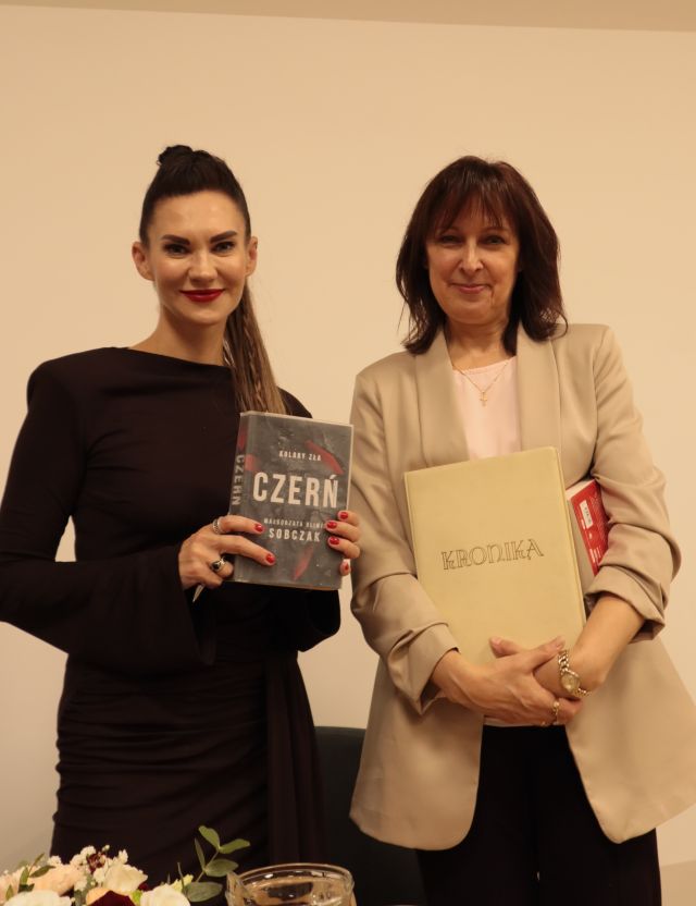 dyrektorka z kroniką biblioteki i autorka z książką pozują do zdjęcia