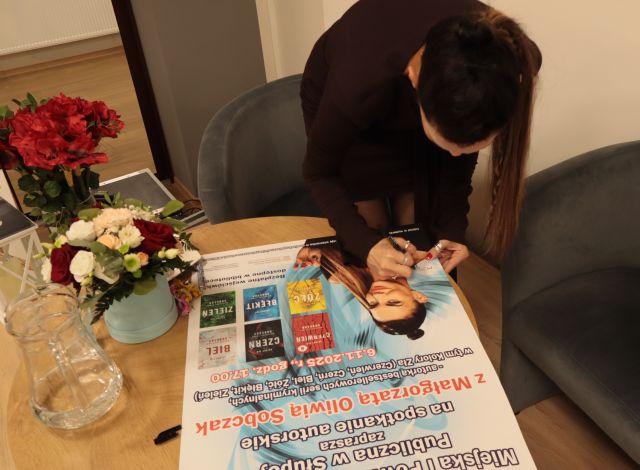 autorka podpisuje się na plakacie