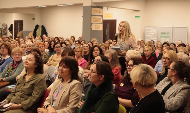 kobieta z publiczności stoi i zadaje pytanie