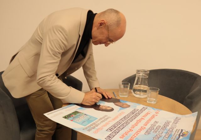 doktor podpisuje się na plakacie reklamującym spotkanie