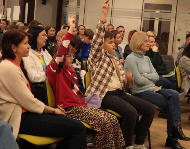 na zdjęciu publiczność siedząca na krzesłach