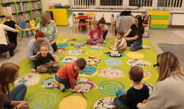 małę dzieci z rodzicami bawią się na kolorowym dywanie