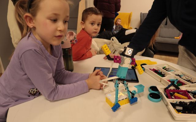 dziewczynka i chłopiec patrzą na robota z klocków LEGO