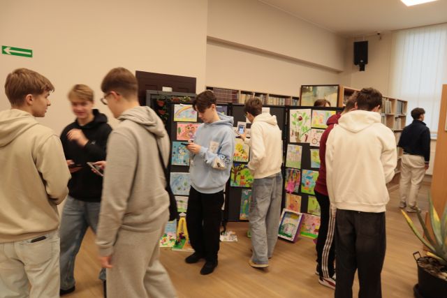 młodzież gra w grę mobilną ze smartfonami w bibliotece