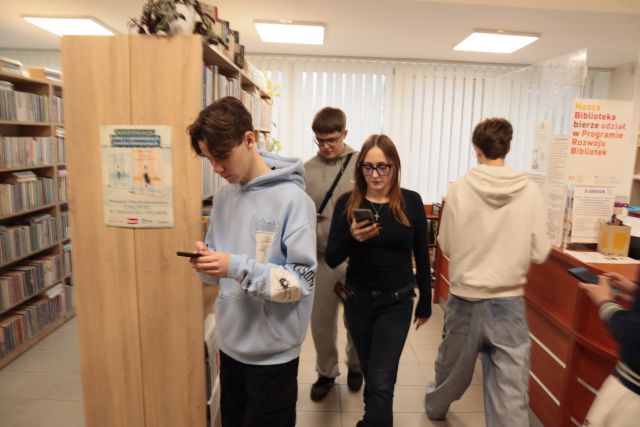 młodzież gra w grę mobilną ze smartfonami w bibliotece