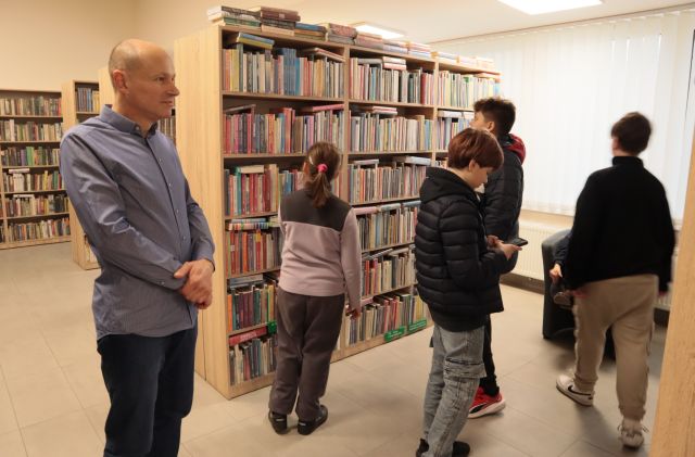 młodzież z nauczycielem między regałami z książkami