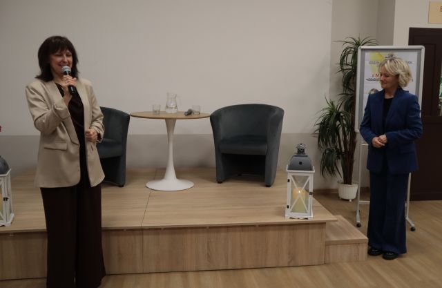 dyrektorka biblioteki z mikrofonem, obok stoi Maria Pakulnis