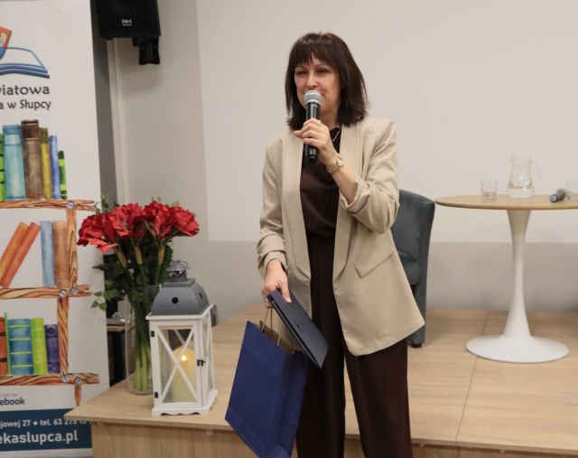 dyrektorka biblioteki z mikrofonem i prezentem