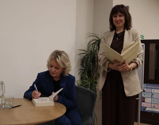 aktorka podpisuje książkę, obok stoi dyrektorka biblioteki z książką