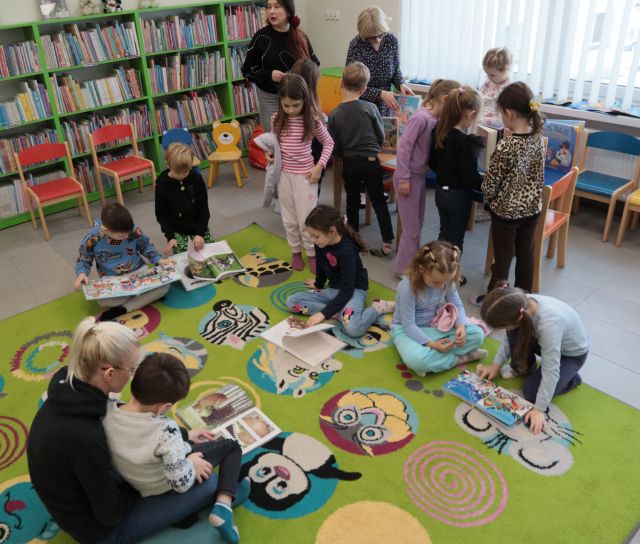 dzieci na kolorowym dywanie przeglądają książki
