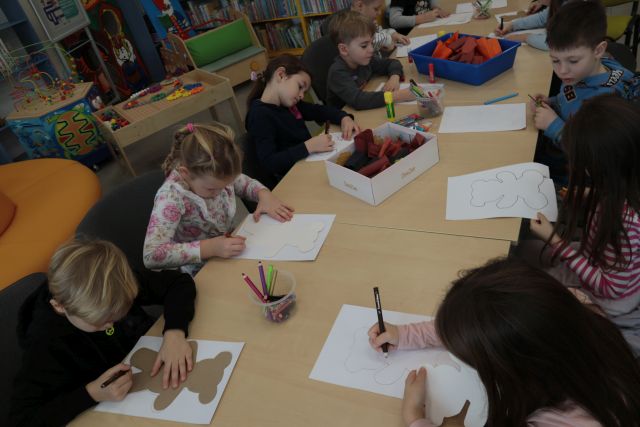 dzieci soedzą przy stołach i malują na kartkach