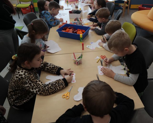 dzieci soedzą przy stołach i malują na kartkach