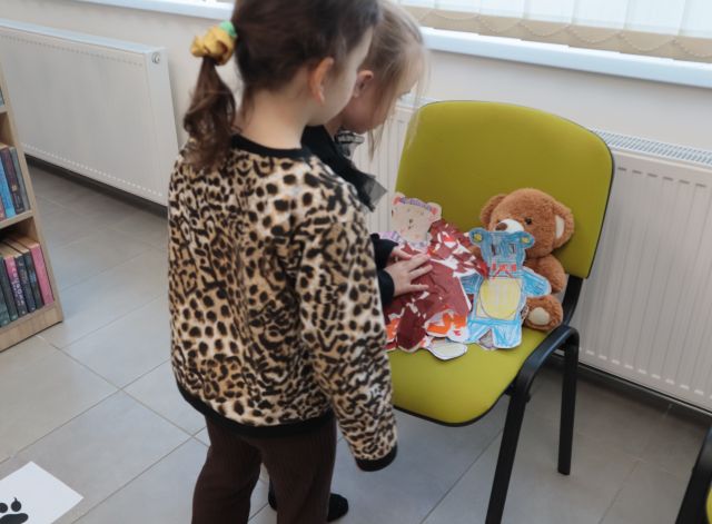 na krześle misie wycięte z kartek i pokorowane i wyklejone przez dzieci, przed krzesłem stoją dwie dziewczynki