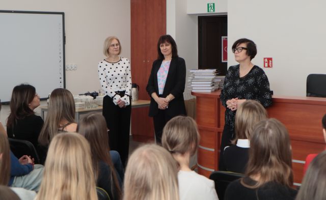 bibliotekarka, dyrektorka biblioteki i nauczycielka stoją przed uczestnikami konkursu siedzącymi na krzesłach