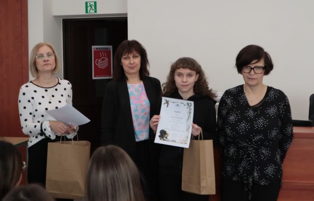 laureatka konkursu z dyplomem i nagrodą pozuje do zdjęcie z bibliotekarką, dyrektorką biblioteki i nauczycielką