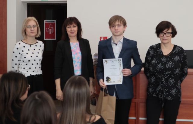 laureat konkursu z dyplomem i nagrodą pozuje do zdjęcie z bibliotekarką, dyrektorką biblioteki i nauczycielką