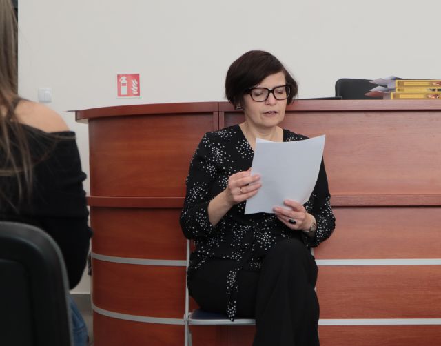 nauczycielka siedzi na krześle i czyta z kartki