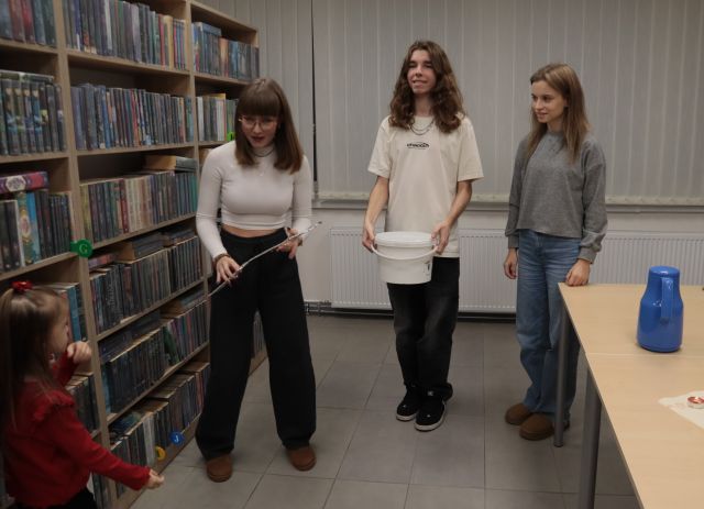 dwie dziewczyny i chłopak stoją z wiaderkiem i kluczem z papieru