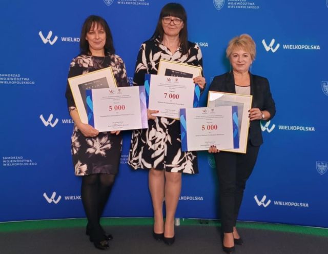 dyrektorka biblioteki z dwiema bibliotekarkami, w dłoniach trzymają dyplomy i czeki
