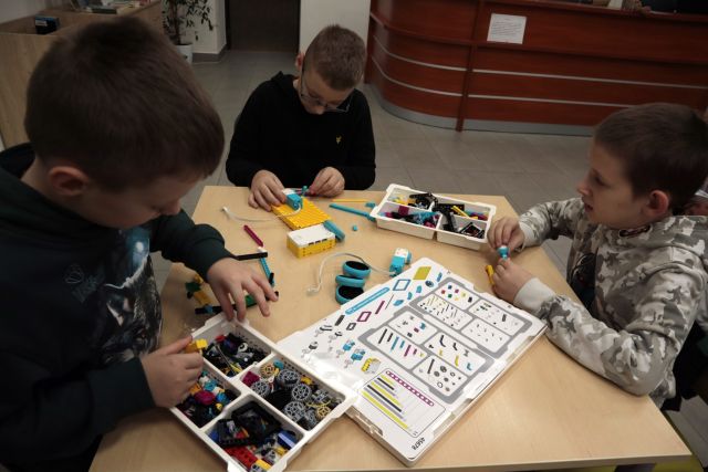3 chłopców buduje z klocków Lego