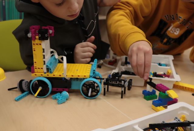 dziecięce dłonie składają pojazd z klocków Lego