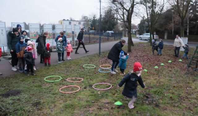dzieci z rodzicami biegają pomiędzy hula hoop