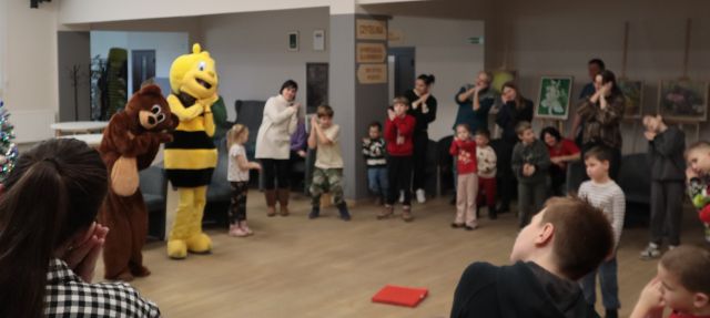 dzieci, rodzice, pszczółka i miś bawią się w rytm muzyki