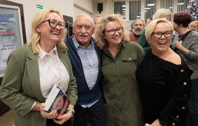 Na zdjęciu znajduję się mężczyzna oraz trzy kobiety, dwie po prawej jedna po lewej. Kobieta po lewej trzyma w rękach książkę i wszyscy pozują do wspólnego zdjęcia.