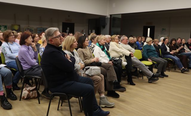 Na zdjęciu znajdują się ludzie z widowni, skierowani w stronę sceny. Zdjęcie zostało wykonane od boku.