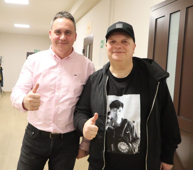 Na zdjęciu znajduje się dwóch mężczyzn pozujących razem do zdjęcia, oboje pokazują kciuk w górę.