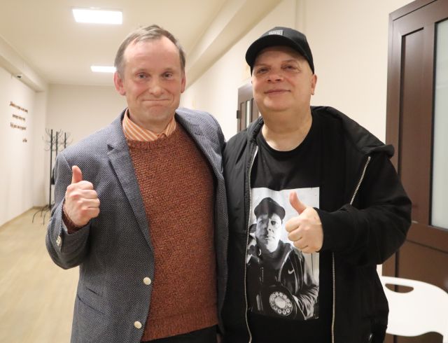 Na zdjęciu znajduje się dwóch mężczyzn stojących do zdjęcia i pokazujących kciuk w górę.